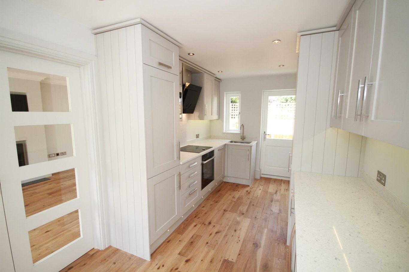 Modern kitchen with wooden flooring, white cabinetry, and natural light.