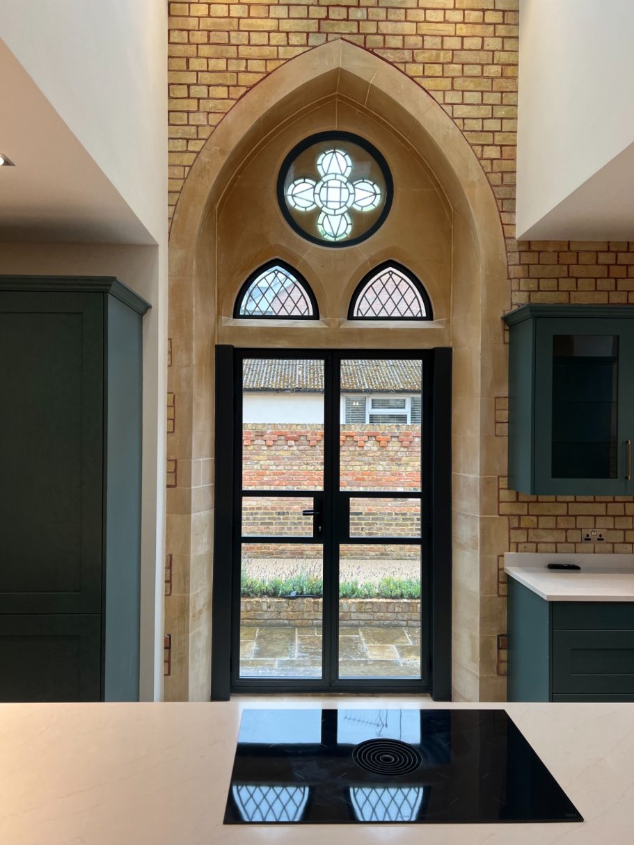Modern kitchen with a gothic-style window featuring decorative glass and a view outdoors.