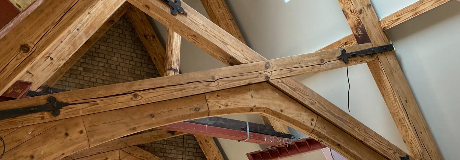 Close-up of rustic wooden beams with metal brackets in a ceiling structure.