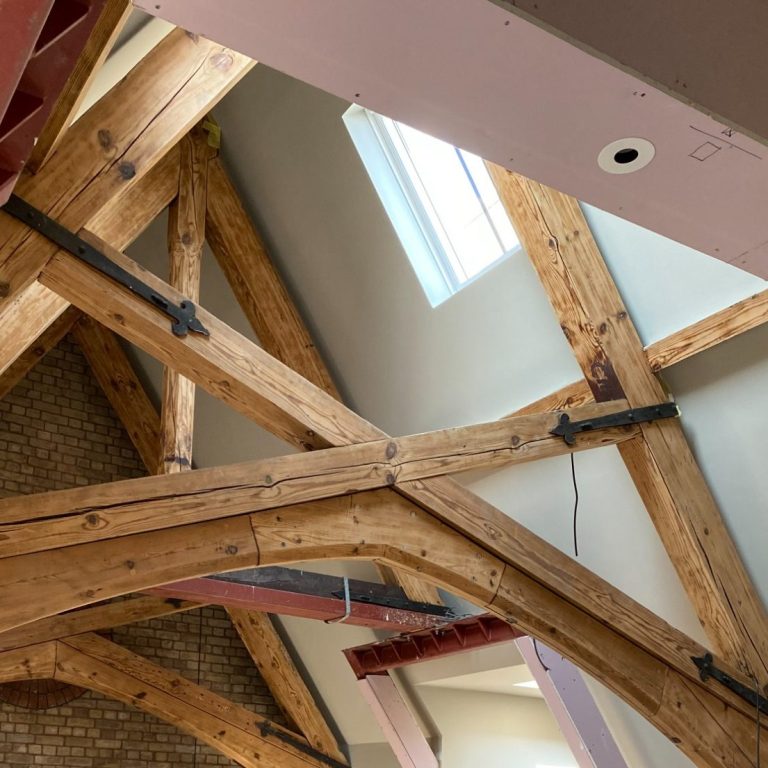 Exposed wooden beams and a skylight in a modern interior space.