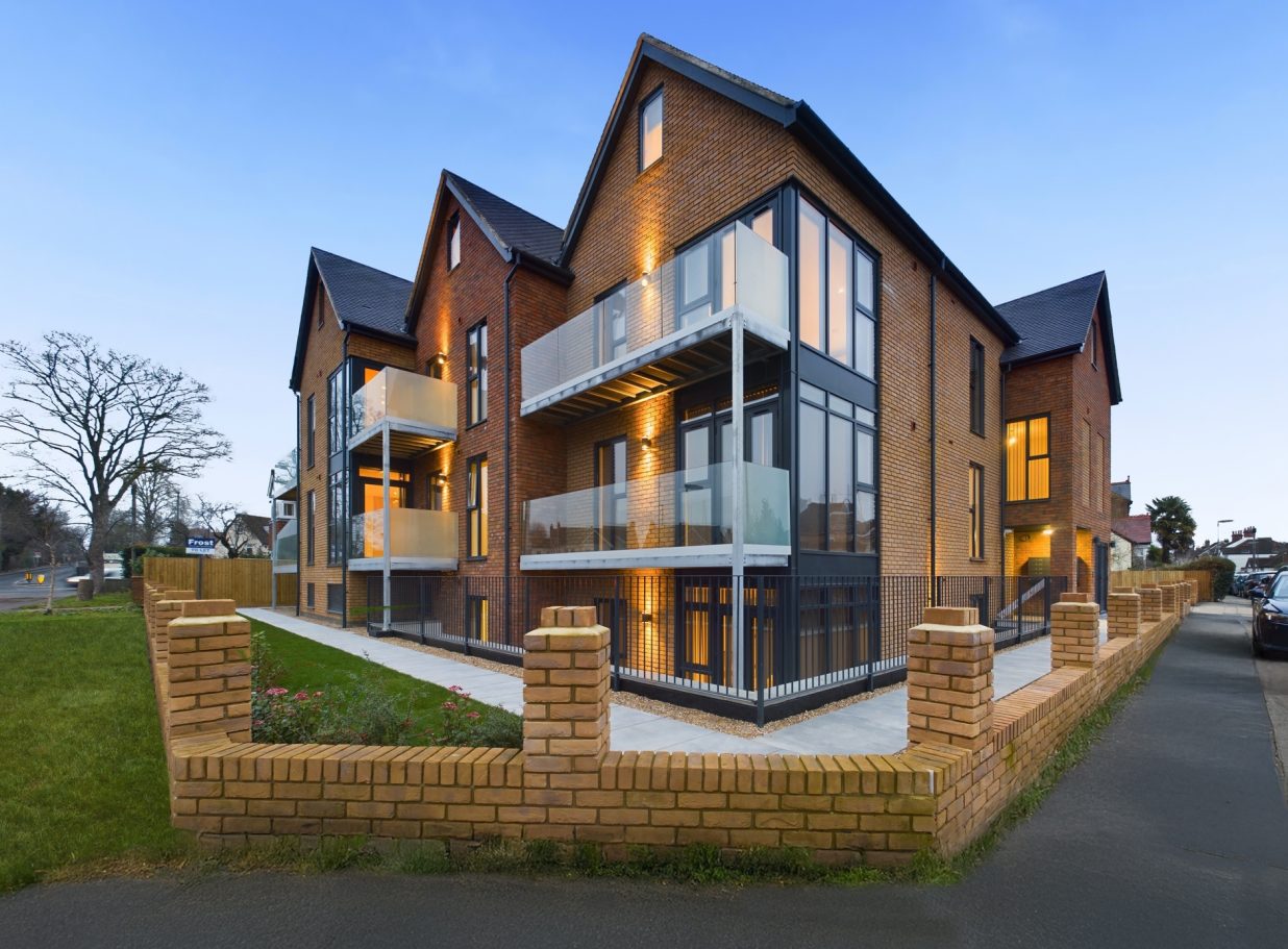 Modern residential building featuring multiple balconies and brick walls.