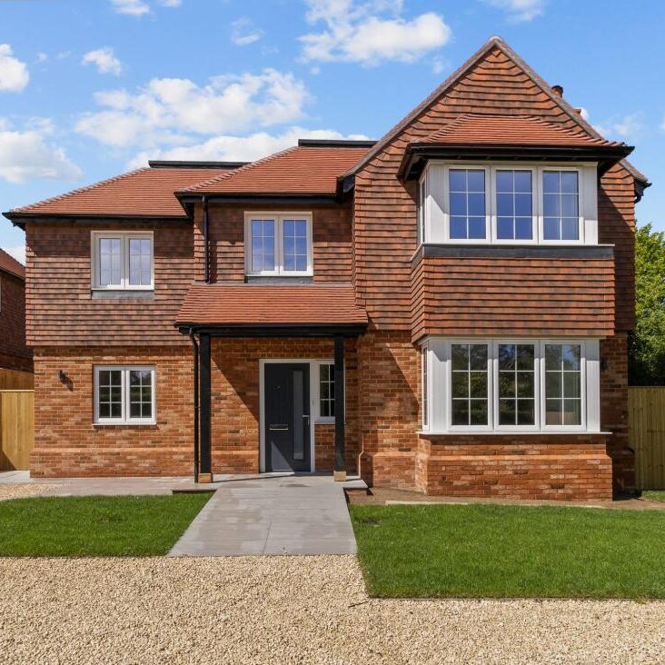 Two-storey detached red-brick house with tiled roof, central doorway and front lawn