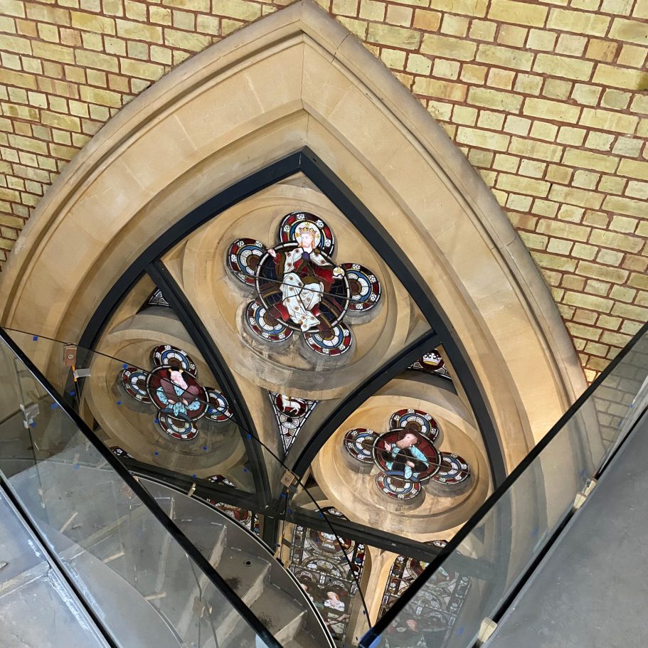 Reflected stained glass window within an arch, viewed from above.