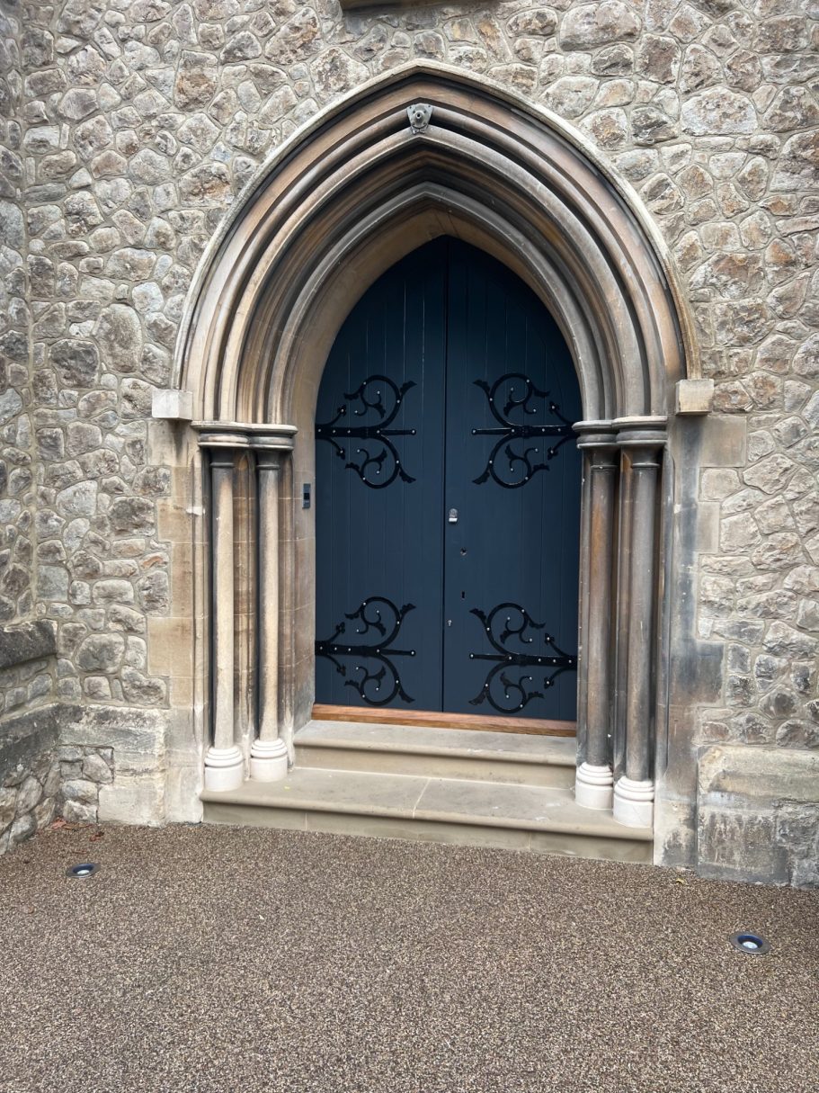 Gothic-style double doors set in a stone wall with decorative black ironwork.